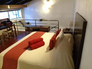 Hotel Boutique Casabella في كواتيبيك: غرفة نوم عليها سرير ومخدات حمراء