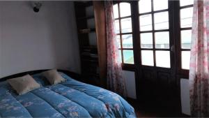 um quarto com uma cama azul e uma janela em Hospedaje compartido SOL em Ushuaia
