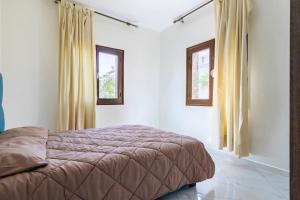 um quarto com uma cama e duas janelas em Appartement chaleureux et calme, Parking, Jardin em Agadir