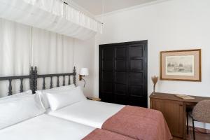 sypialnia z białym łóżkiem, biurkiem i łóżkiem o wymiarach 60 cm w obiekcie Parador de Ciudad Rodrigo w mieście Ciudad-Rodrigo