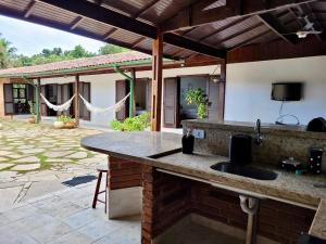 an outdoor kitchen with a sink and a patio at Casa Enorme em condominio, 4 suites, piscina com cascata, cozinha gourmet com churrasueira e fundo com pier no rio para práticas aquaticas in Bertioga