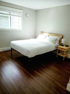 a bedroom with a white bed and a wooden floor at BlueBack BeachFront 2-Bedroom Private Apartment in Nanaimo