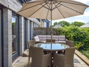 a table and chairs with an umbrella on a patio at Bluebell Barn in Grampound