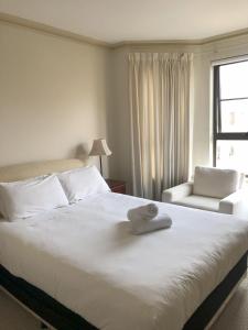 a bedroom with a large white bed and a chair at Superb Stay in Adelaides East End in Adelaide