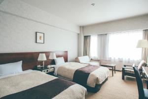 a hotel room with two beds and a window at Kanazawa Kokusai Hotel in Kanazawa