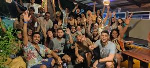 a group of people posing for a picture with their hands in the air at Iduna Hostel in Pipa