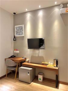 una camera con scrivania e TV appesa a un muro di oxy suites 1-03 at Shop House Meisterstadt Pollux Habibie a Batam Center