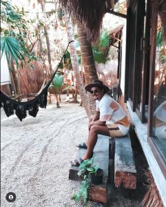 a woman sitting on a bench next to a hammock at Pal Mar Glamtainer Tulum in Tulum