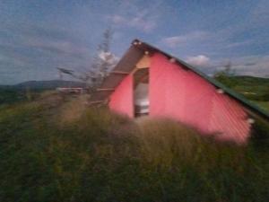 eine rote Scheune auf einem Feld mit hoher Wiese in der Unterkunft Mirador Valle de la Tatacoa in Villavieja