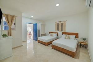 a bedroom with two beds and a blue door at Suites Ha in Isla Mujeres