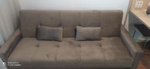 Un sofá marrón con dos almohadas. en Flat 4 Estrelas Pinheiros, en São Paulo