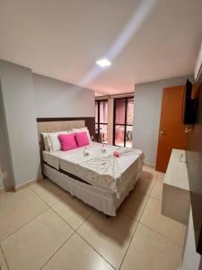 um quarto com uma cama grande e almofadas cor-de-rosa em Apartamento a beira-mar com piscina em Cabedelo