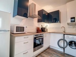 cocina con armarios blancos y microondas en Maison Port-en-Bessin-Huppain, 3 pièces, 4 personnes - FR-1-746-9, en Port-en-Bessin-Huppain