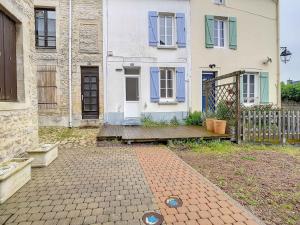 una casa con un banco de madera delante de ella en Maison Port-en-Bessin-Huppain, 3 pièces, 4 personnes - FR-1-746-9, en Port-en-Bessin-Huppain