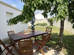 einen Holztisch und Stühle unter einem Baum in der Unterkunft Maison spacieuse proche plage avec jardin et terrasse – 3 chambres, 6 couchages, calme assuré - FR-1-224-805 in Saint-Gilles-Croix-de-Vie
