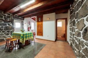 Cette chambre dispose d'une table et d'un mur en pierre. dans l'établissement holiday home, Praínha de Baixo, Pico, Azores, à Prainha de Baixo