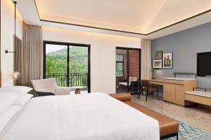 ein Hotelzimmer mit einem Bett, einem Schreibtisch und einem TV in der Unterkunft Four Points by Sheraton Hainan, Qiongzhong in Qiongzhong