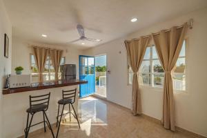 a kitchen with two stools at a bar with windows at Suites Ha in Isla Mujeres