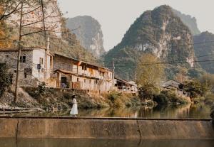 una mujer con un vestido blanco parada en un puente sobre un río en Yen Nhi Homestay Ban Gioc - New CS2, en Cao Bằng