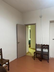 une pièce vide avec deux chaises et une porte dans l'établissement tamila's guesthause, à Mestia