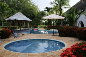 uma piscina com uma mesa e um guarda-sol e flores em Family 2bd apt near Quepos/Manuel Antonio em Quepos