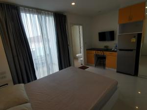 une chambre avec un lit et une cuisine avec une grande fenêtre dans l'établissement Daisy Residence, à Jomtien Beach