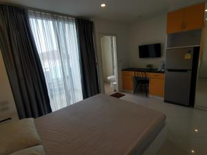 een kamer met een bed en een keuken met een groot raam bij Daisy Residence in Jomtien Beach