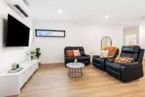 a living room with two black chairs and a flat screen tv at City Edge Apartment 1 (Wheelchair Accessible) in Mount Gambier