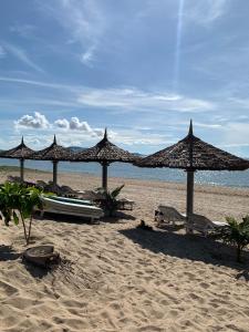 una playa con sombrillas y un barco en la arena en Full Moon Village Resort, en Mui Ne