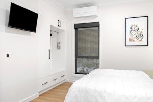 a white bedroom with a bed and a window at City Edge 2 Apartment - Wheelchair Accessible in Mount Gambier