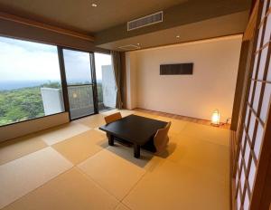 那須 にごり湯の大浴場露天風呂があるホテルコンドミニアム في Nasu-yumoto: غرفة معيشة مع طاولة ونوافذ كبيرة
