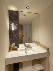 uma casa de banho com um lavatório e um espelho grande em 那須 にごり湯の大浴場露天風呂があるホテルコンドミニアム em Nasu-yumoto