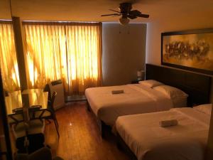Habitación de hotel con 2 camas y ventilador de techo. en Hotel Las Condes, en Trujillo