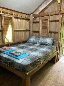 a large bed in a room with wooden walls at Toh Tao Homestay 