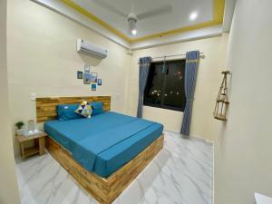 a bedroom with a blue bed and a window at Nhật Lệ Oyster House in Dong Hoi
