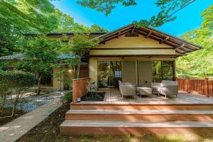 a home with a deck with chairs and a house at じぇーむすのおうち in Yawatano