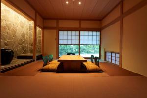 Zimmer mit einem Tisch und Stühlen sowie einem großen Fenster in der Unterkunft じぇーむすのおうち in Yawatano