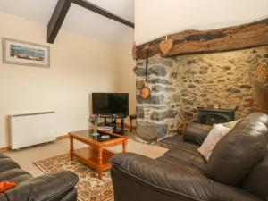 a living room with a couch and a stone fireplace at Ty Hen in Pwllheli