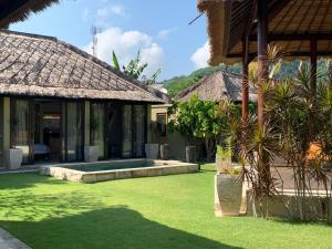a courtyard of a house with grass and trees at Seaside Villa Kecil in Sekotong