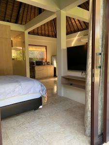a bedroom with a bed and a flat screen tv at Seaside Villa Kecil in Sekotong