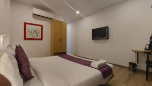 a bedroom with a white bed and a tv on the wall at Hotel Mavens Orange Gurgaon in Gurgaon