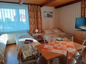 a room with two beds and a table and a television at Pokoje Gucio in Łeba