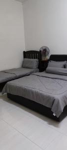 dwa łóżka siedzące obok siebie w sypialni w obiekcie As-Salam Homestay w mieście Sungai Petani