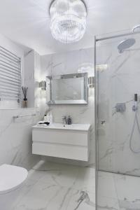 a white bathroom with a sink and a shower at Top Apartment - Playa Baltis in Międzyzdroje