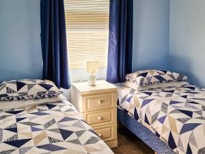 two beds in a bedroom with blue walls and a night stand at Seabreeze in Llangain