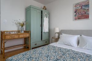 Nona Vi - Boutique Stone House في بول: غرفة نوم مع خزانة زرقاء وسرير مع طاولة