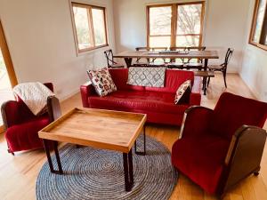 sala de estar con sofá rojo y mesa en Booroolgunyah Luxury Farm Stay, en Booroolite