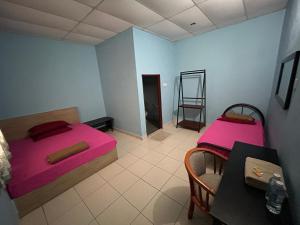 a room with two beds and a table and a chair at Dtahan Motel Taman Negara in Kuala Tahan