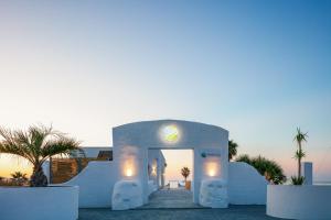 a white villa with a sunset in the background at Thalasses in Adelianos Kampos