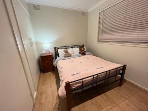 a bedroom with a bed with two teddy bears on it at Cosy 3 bedroom family home near beach and shops in Frankston